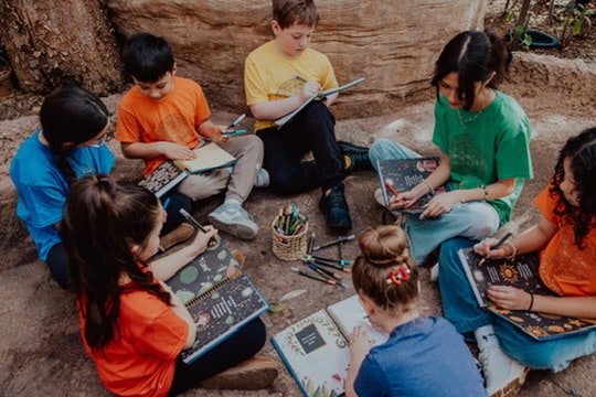 Children sitting in a circle, each writing in a Friendship Journal